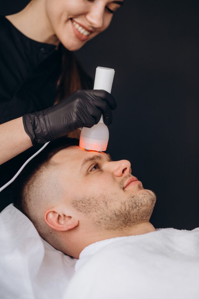 Young woman getting chromotherapy procedure for face skin rejuvenation